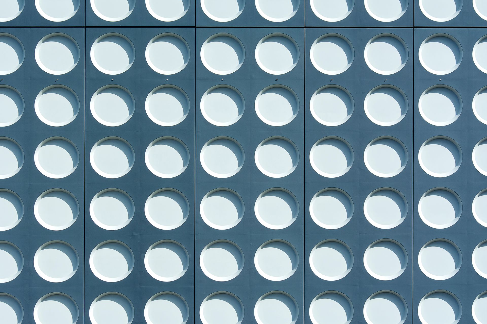 An abstract view of a modern building facade featuring circular recesses creating geometric patterns.