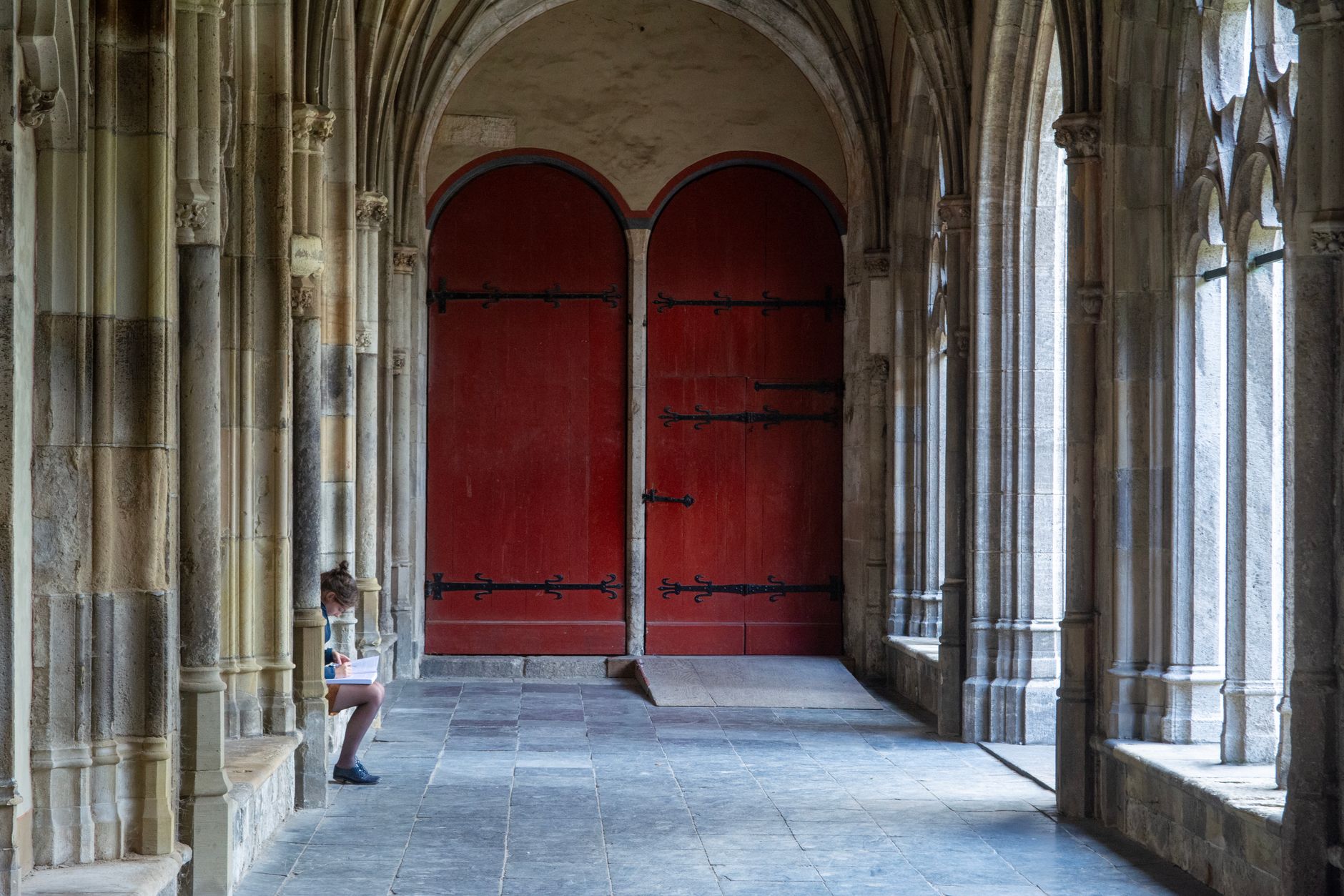 A serene Gothic cloister scene in Utrecht featuring red doors and ancient stone arches.