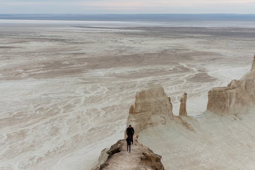 A person standing on top of a cliff in the desert