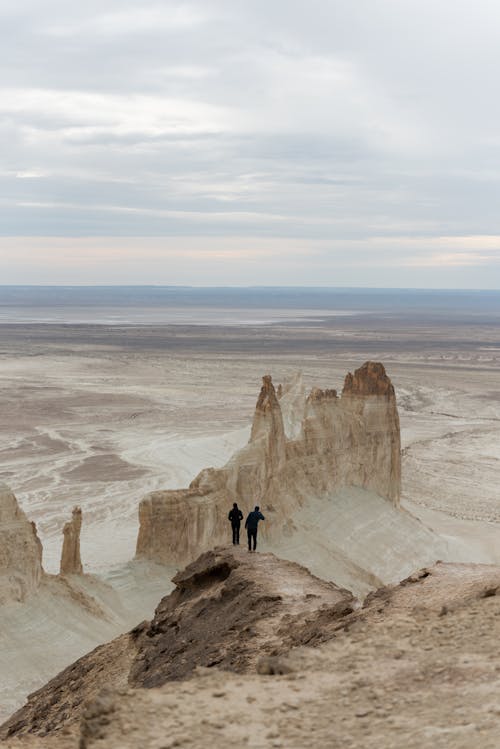 Two people standing on top of a mountain with a view of the desert