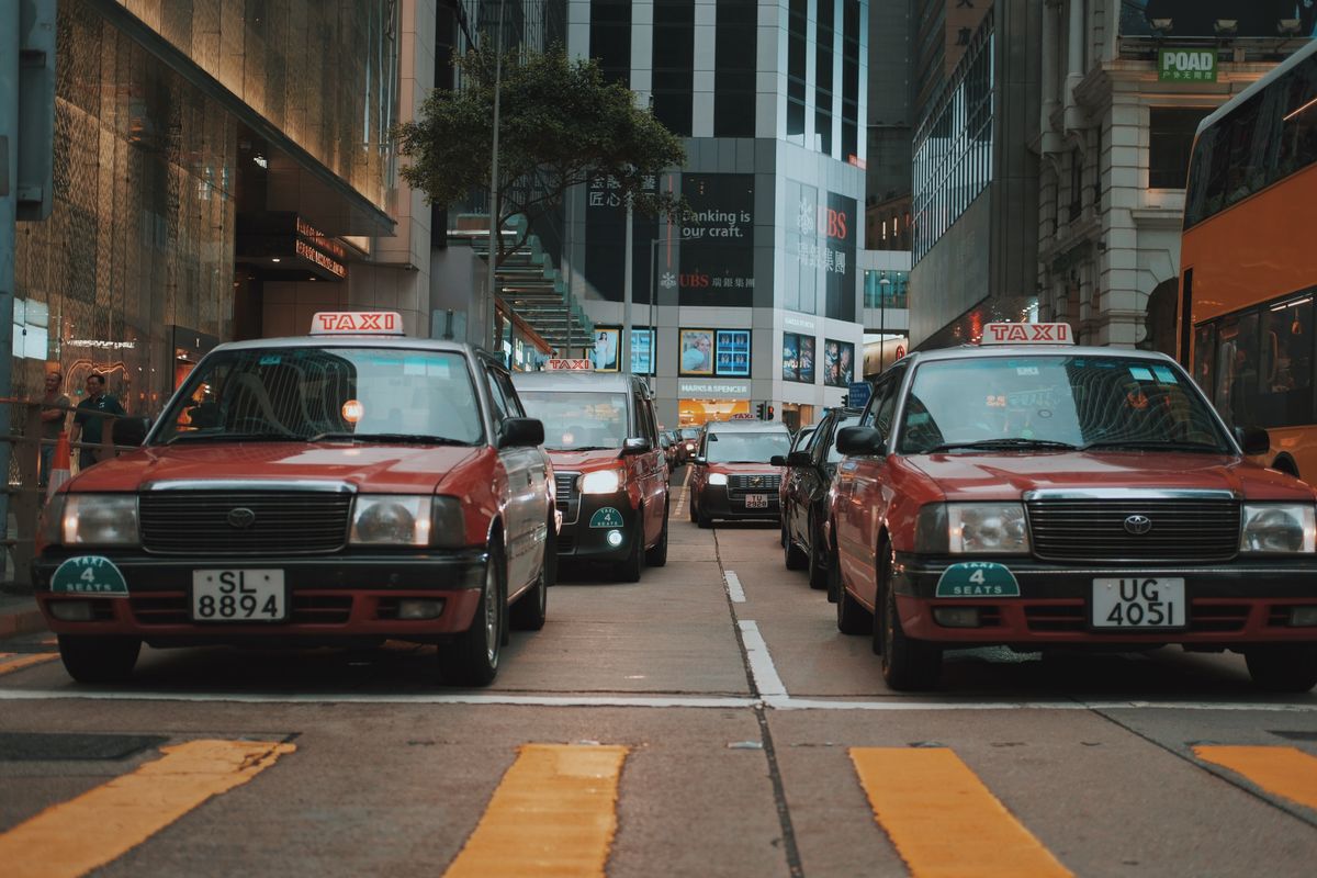 Red Toyota Crown Comfort taxis on a street in Hong Kong showing the city's iconic red vehicle culture