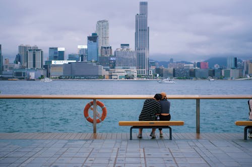 Two people sitting on a bench overlooking a city