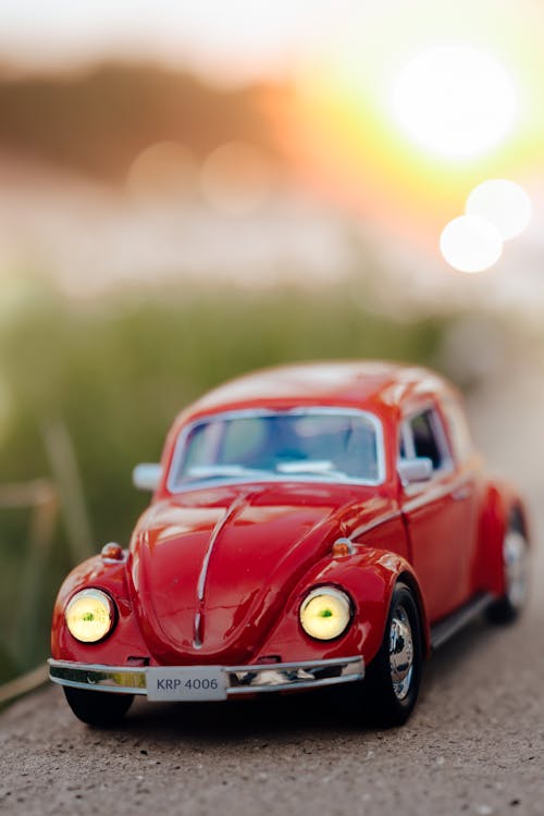 A toy car is parked on a road with the sun setting in the background