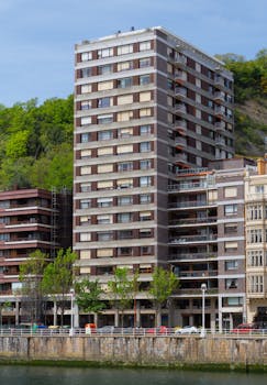 High-rise apartment buildings along Nervión River in Bilbao, with lush greenery.
