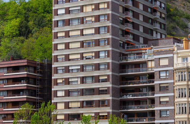 High-rise apartment buildings along Nervión River in Bilbao, with lush greenery.