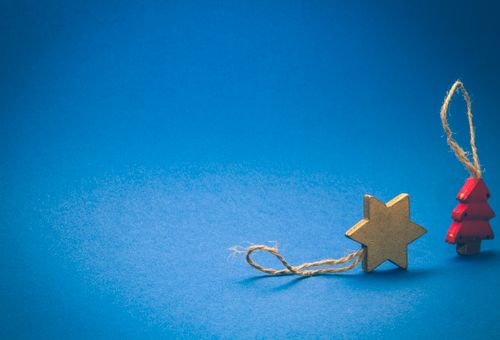Free A wooden star and Christmas tree ornament on a vibrant blue background, symbolizing the holiday season. Stock Photo