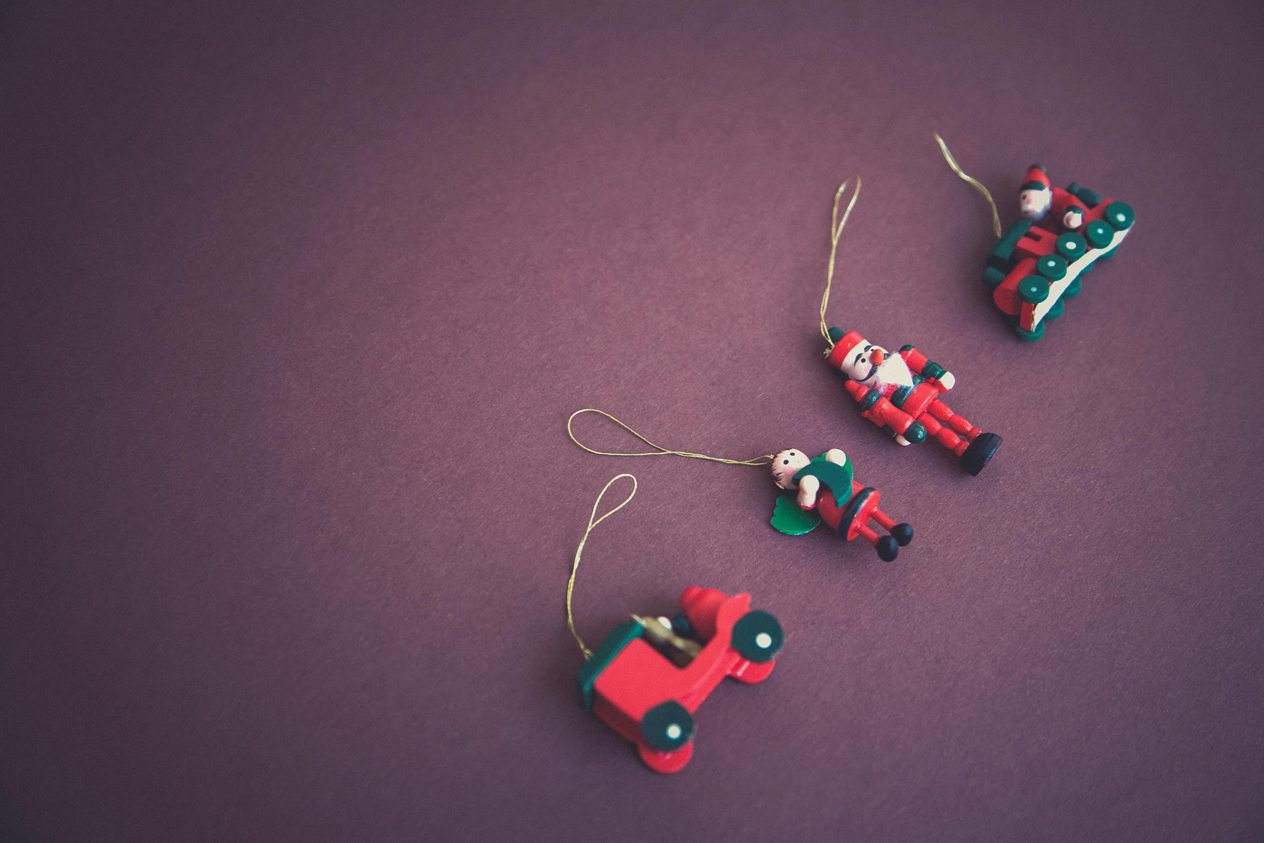 A minimalist flat lay of Christmas ornaments featuring Santa and toys on a purple background.