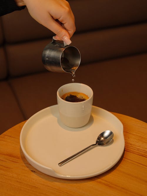 Free A person pouring coffee into a cup on a plate Stock Photo