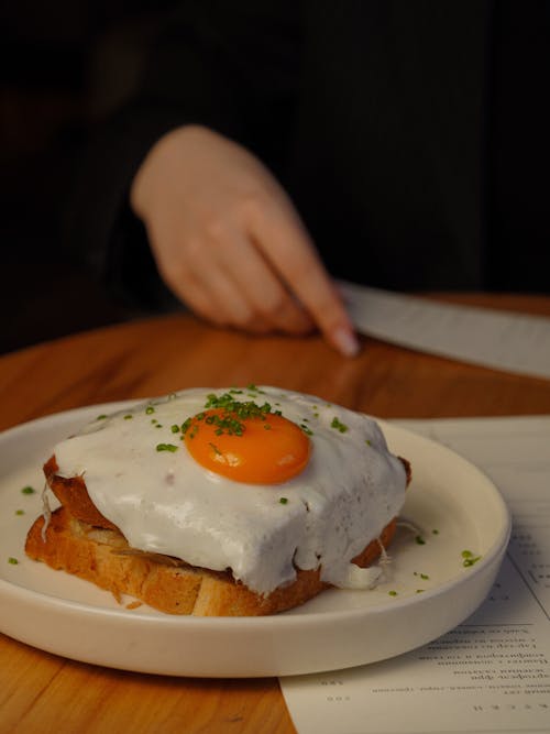 A person is holding a knife and fork over a plate of food