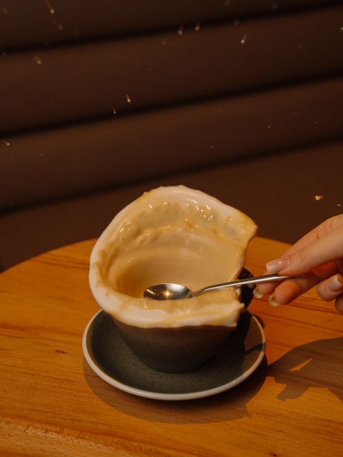 Free Close-up of a spilled coffee cup and a hand holding a teaspoon, capturing motion. Stock Photo