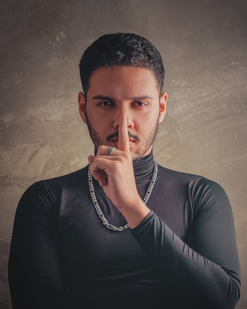 Free A man in a black shirt is making a finger to his lips Stock Photo