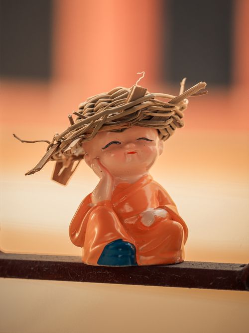 Free A delicate porcelain figurine with a straw hat sits in warm sunlight. Stock Photo