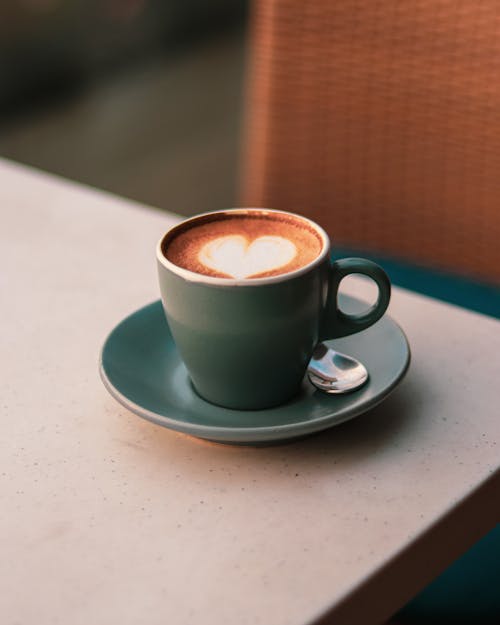 A cup of coffee on a table with a heart shape on it