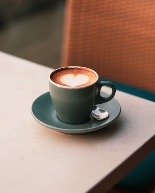 Free A cup of coffee on a table with a heart shape in the middle Stock Photo