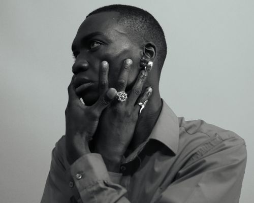 Free A striking black and white portrait showcasing a man's thoughtful expression with distinctive jewelry. Stock Photo
