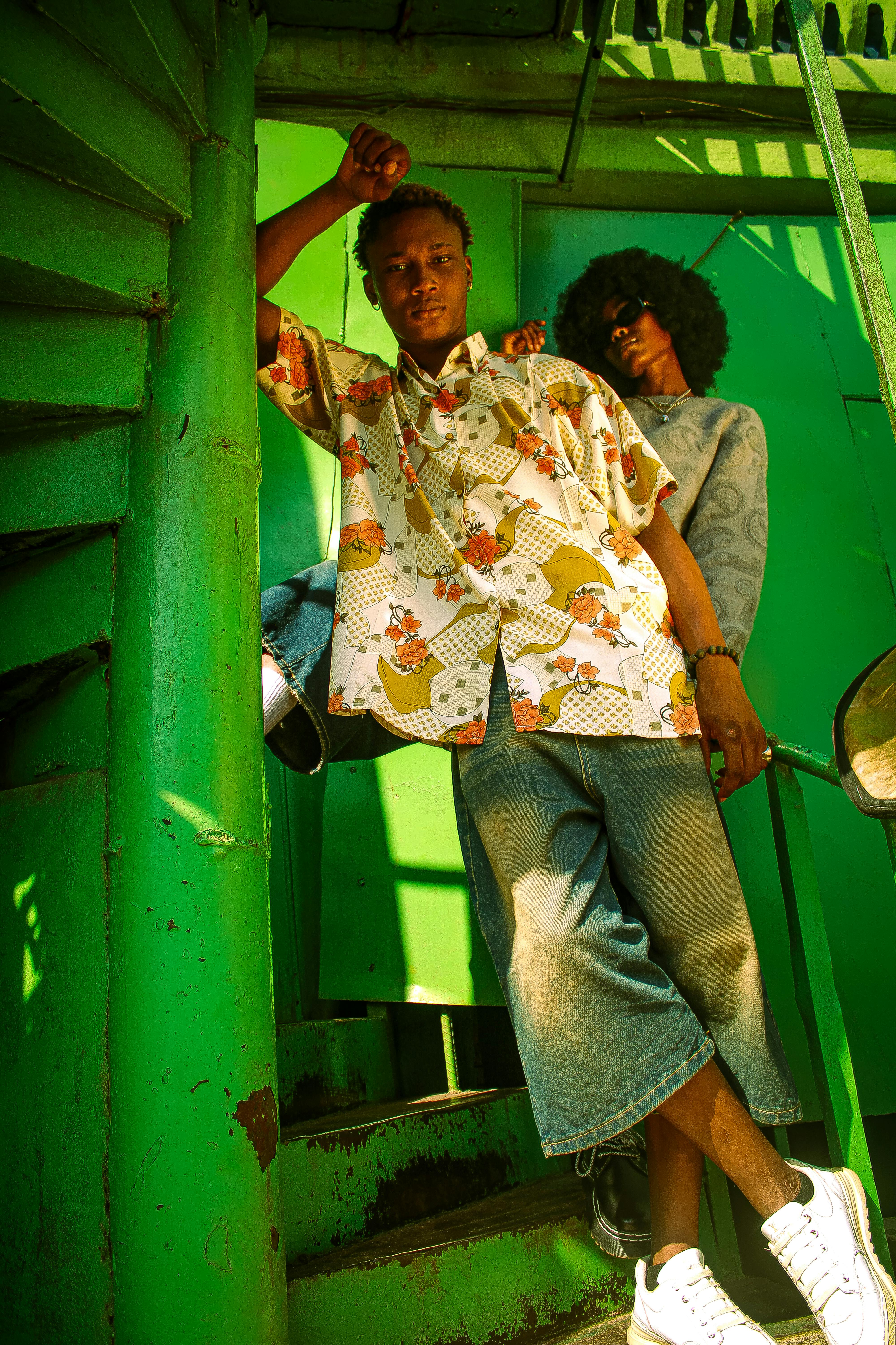 Two adults posing confidently in trendy summer outfits on a green staircase.