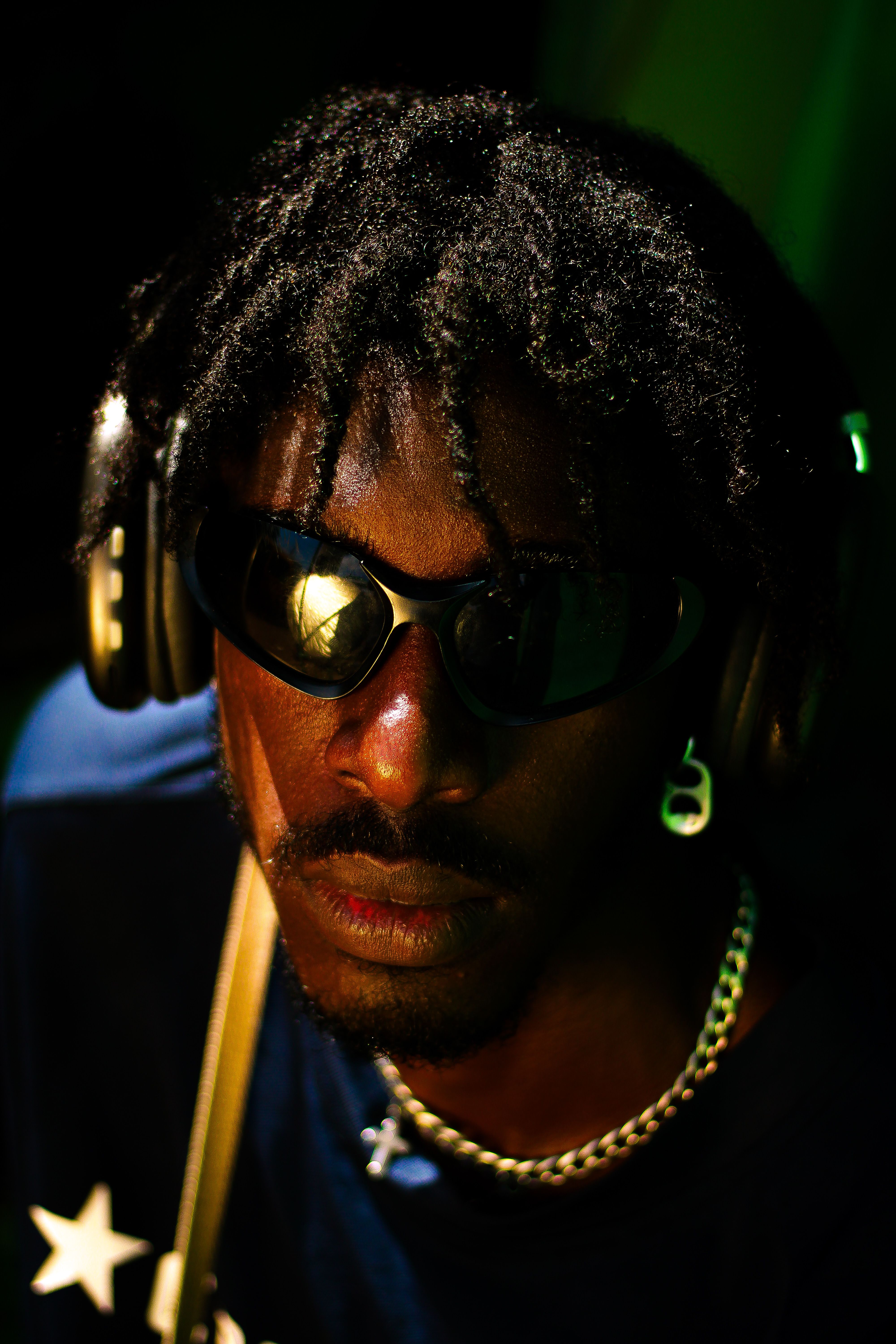 Close-up portrait of a man wearing headphones and sunglasses with a cool, vibrant vibe.