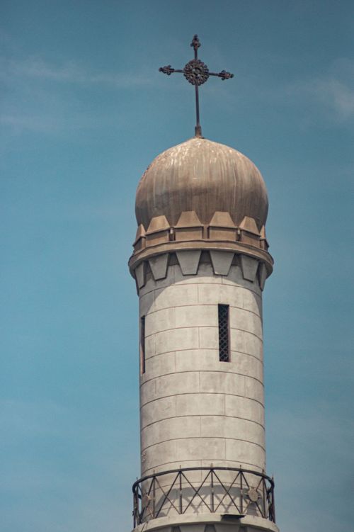 Free A close-up shot of a historic church tower featuring a dome and cross against a clear blue sky. Stock Photo