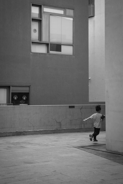 Free Black and white photo of a child running on city pavement, capturing motion and urban life. Stock Photo