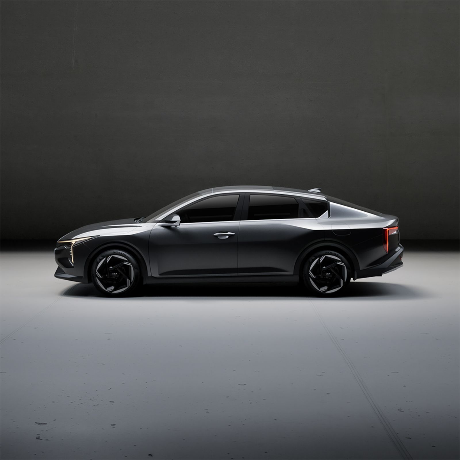 Dark grey executive sedan in side profile in a studio