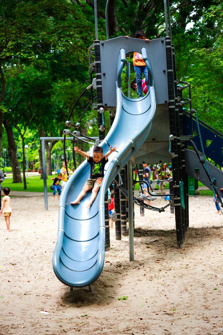 Boy Playing On Slide In Playground