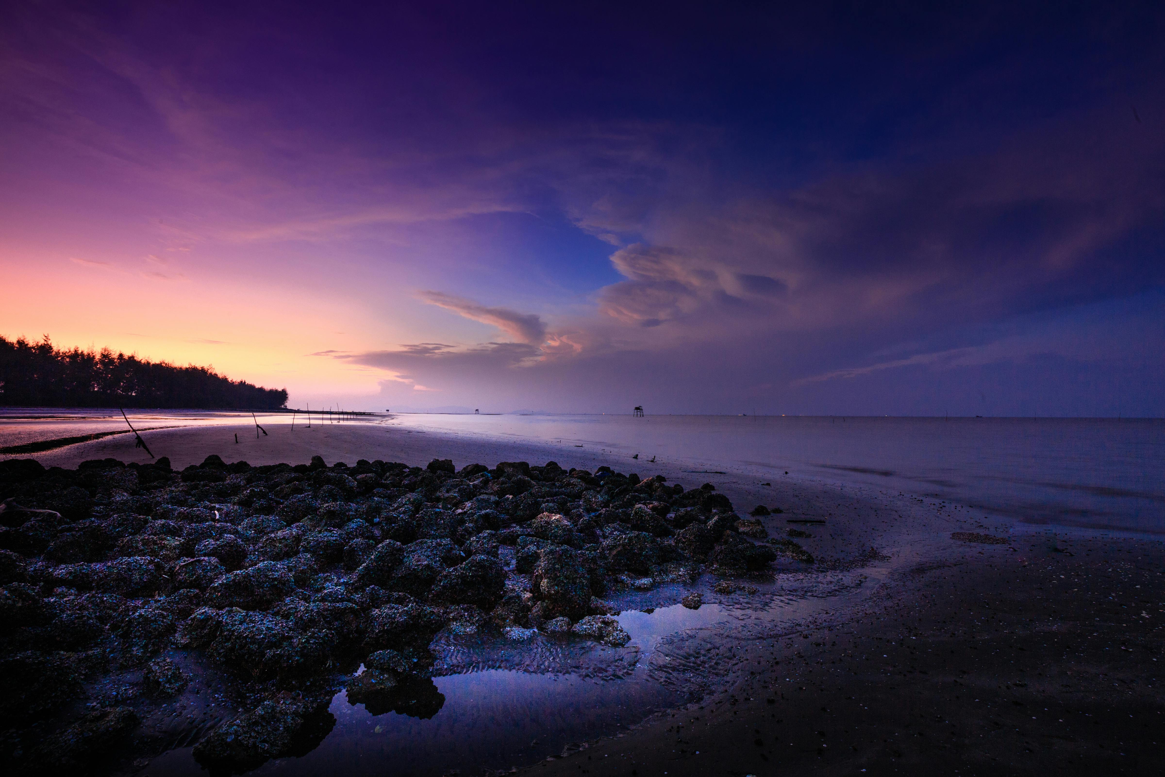 暮光下的海滩宁静祥和，天空与水中倒影色彩斑斓