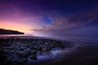 暮光下的海滩宁静祥和，天空与水中倒影色彩斑斓