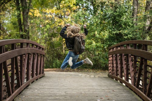 Free Girl Jumping on the Bridge Wearing Black Jacket Stock Photo