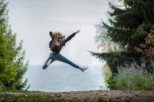 Gratis Wanita Jumping Mengenakan Tas Ransel Hijau Foto Stok