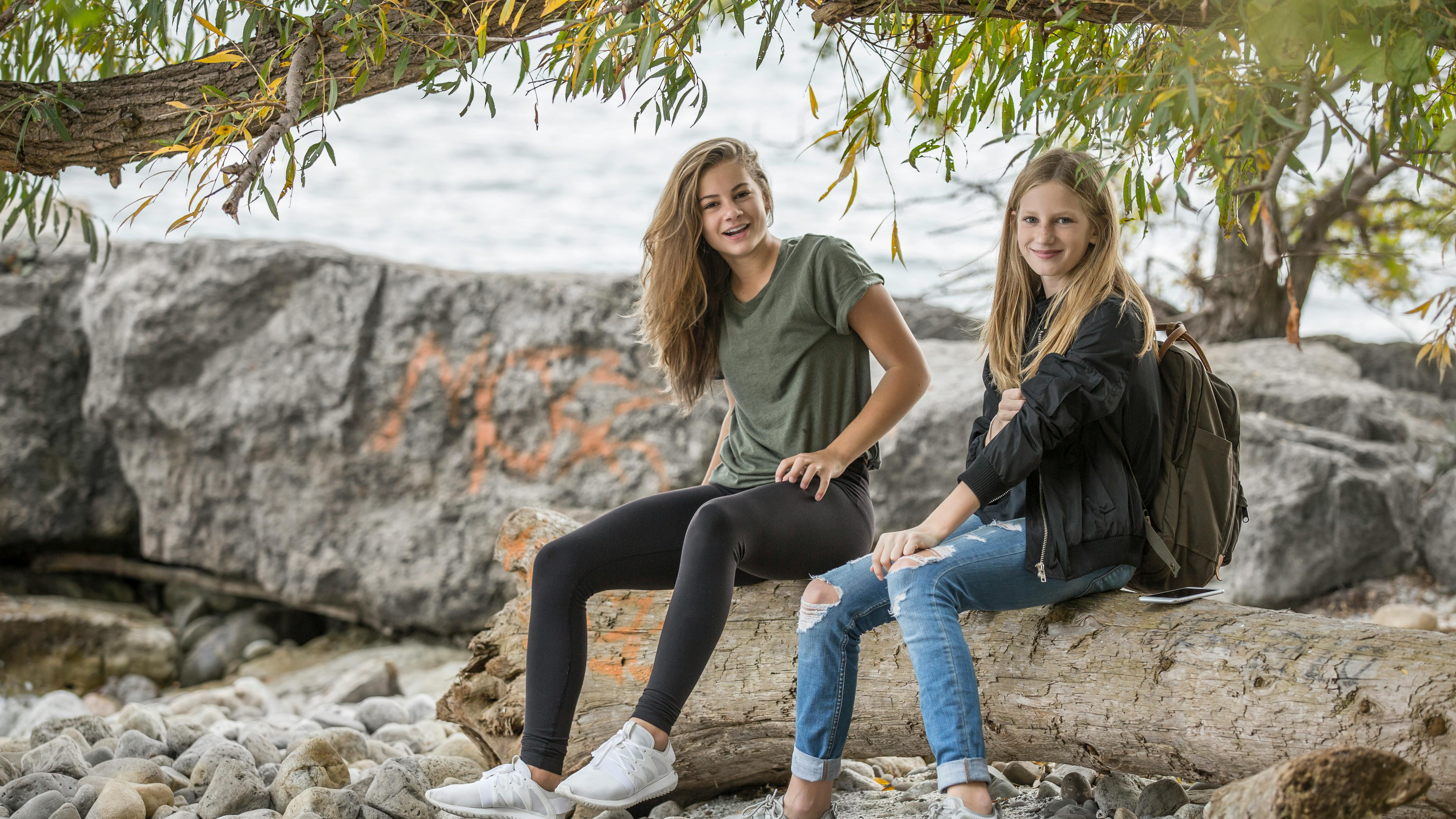 2 women sitting on rock during daytime