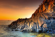 温暖的暮光中，岩石海岸线的壮丽景色被映照得格外突出，尽显自然构造之美