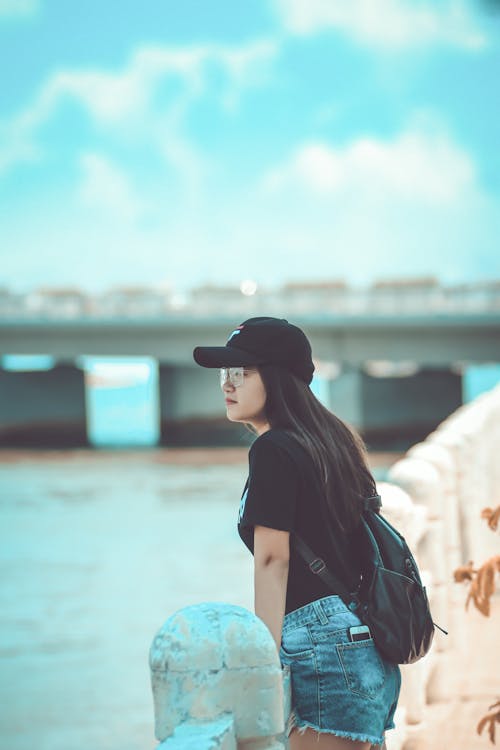 Photo of Woman Leaning on Stone Railing Overlooking Water