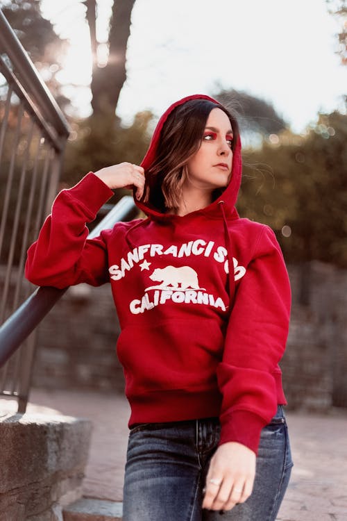 Woman Wearing Red and White Pullover and Blue Faded Jeans
