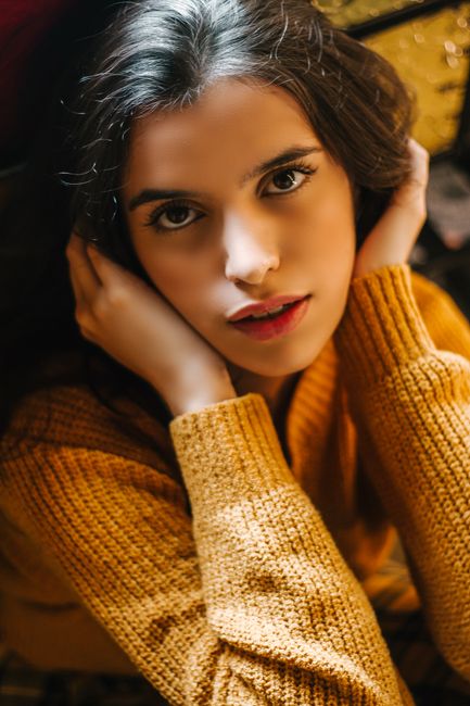 Elegant close-up portrait of a woman with warm lighting and cozy atmosphere.