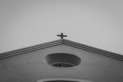 Free Black and white image of a church gable with a cross, evoking a somber religious mood. Stock Photo