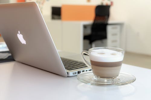 Free Macbook Pro Besides Clear Glass Mug Stock Photo