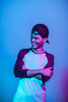 一名穿着休闲装的年轻人在灯光缤纷、充满活力的工作室里自信地微笑着