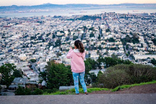 Girl Wearing Pink Hoodie Taking Photo of City