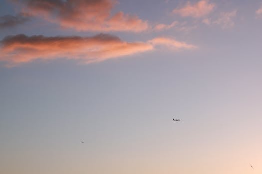 一张飞机剪影的极简主义照片，拍摄于黄昏时分五彩斑斓的云霞天空下