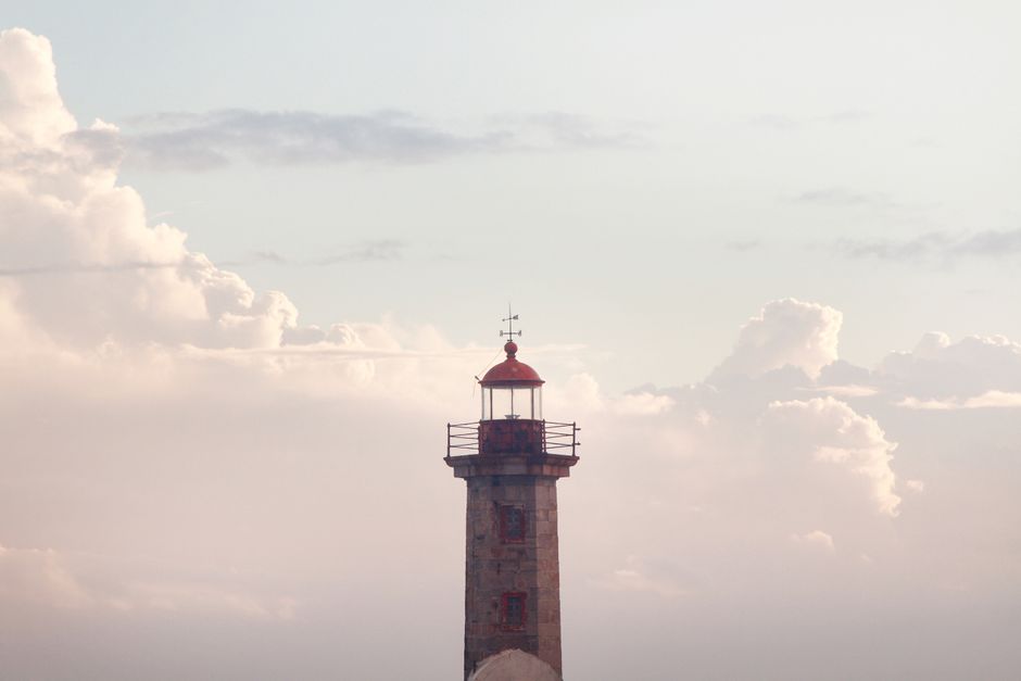 A picturesque lighthouse set against a dramatic cloudy sky in Portugal, evoking a sense of calm and tranquility.