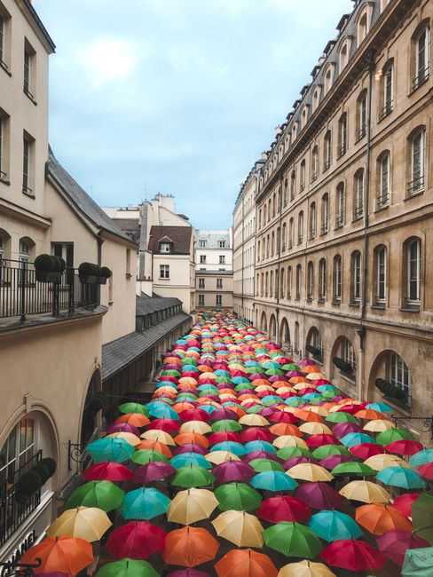 Colorful umbrellas adorn a street in a vibrant Parisian architecture scene.