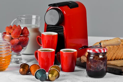 免费 红色陶瓷杯装满咖啡在桌子上的果酱罐附近 素材图片