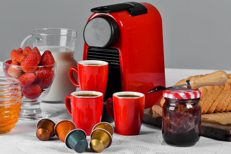 Red Ceramic Mug Filled With Coffee Near Jam Jar On Table