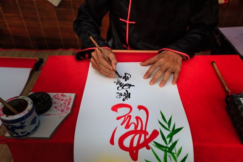 Free An artist skillfully creating traditional calligraphy on a sheet with intricate designs. Stock Photo