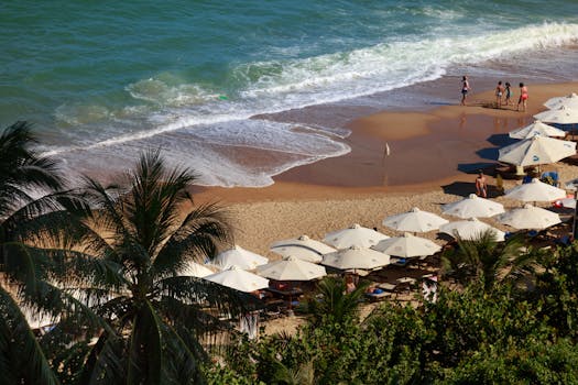 A vibrant coastal view featuring palm trees, beach umbrellas, and people enjoying a sunny day.