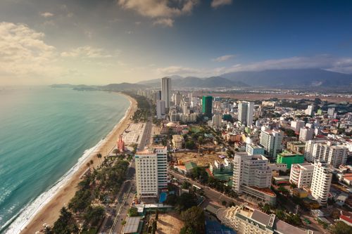 Free Aerial view of a coastal cityscape with beach and mountains. Stock Photo