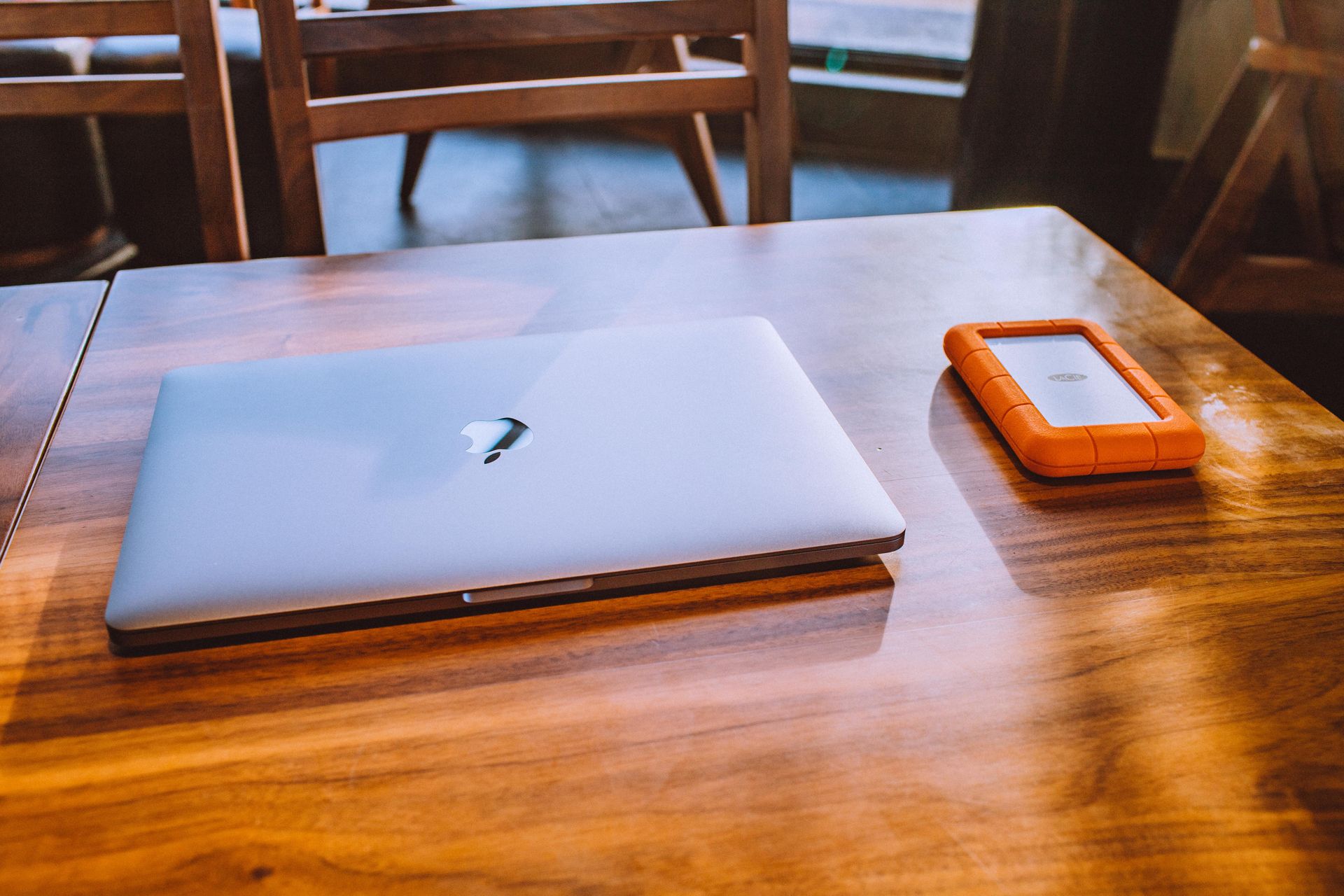 A sleek laptop and rugged external drive on a stylish wooden table in a contemporary indoor setting.