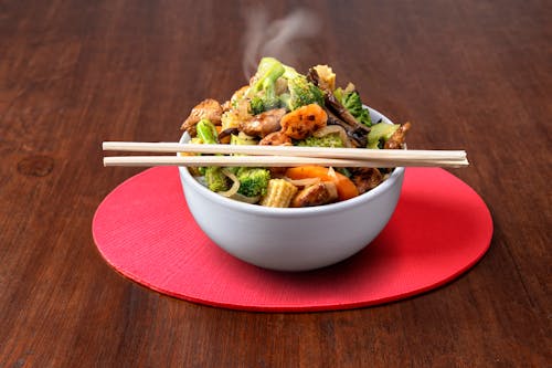 A bowl of stir fry with chopsticks on top