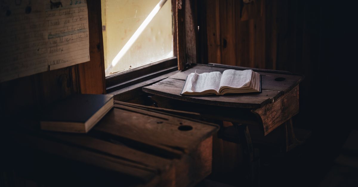 A cozy, dimly lit room with a rustic wooden desk and an open book by a window, evoking calmness.