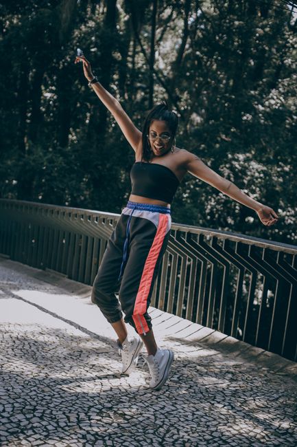 Energetic young woman dancing on a bridge surrounded by nature.